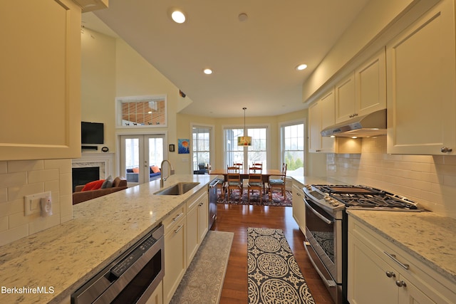 kitchen with white cabinets, a sink, dark wood finished floors, under cabinet range hood, and appliances with stainless steel finishes
