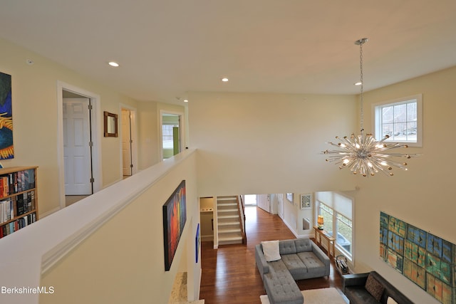 hallway featuring recessed lighting, a towering ceiling, an inviting chandelier, dark wood-type flooring, and stairs