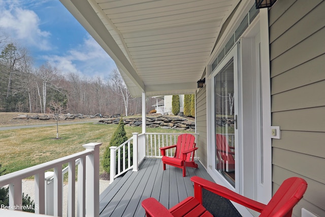 wooden terrace with a lawn and a porch