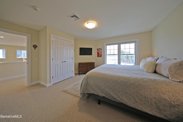 carpeted bedroom featuring a closet, visible vents, baseboards, and multiple windows
