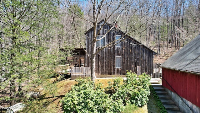 view of home's exterior featuring a chimney, a deck, and a wooded view