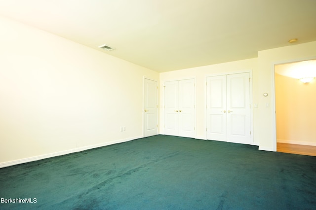 232 Harrington Rd, Otis, MA 01253 - unfurnished bedroom featuring two closets, baseboards, and dark carpet
