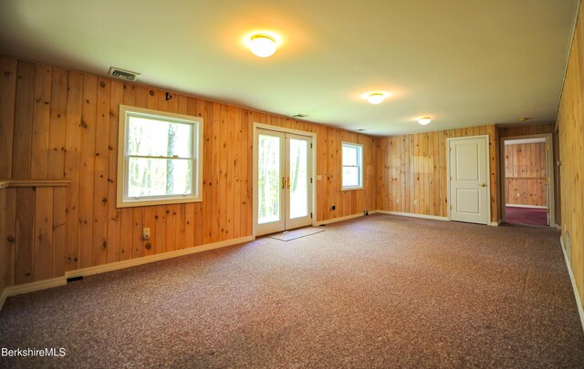 232 Harrington Rd, Otis, MA 01253 - carpeted empty room featuring healthy amount of natural light, french doors, wooden walls, and baseboards