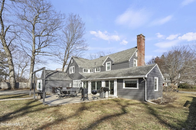 back of property with a patio area, roof with shingles, and a chimney