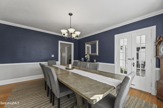 dining room with baseboards, an inviting chandelier, wood finished floors, and ornamental molding