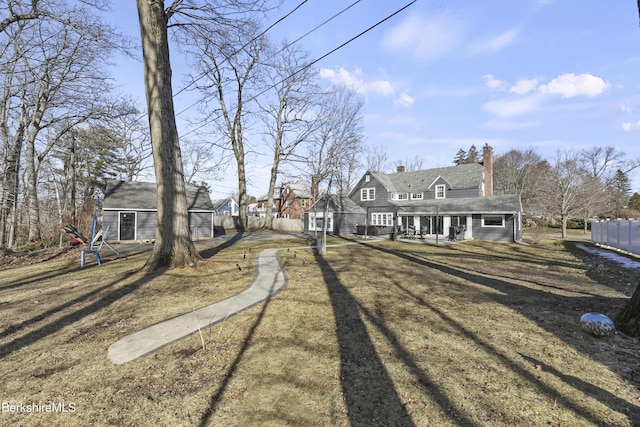 rear view of house with a chimney, an outdoor structure, and fence