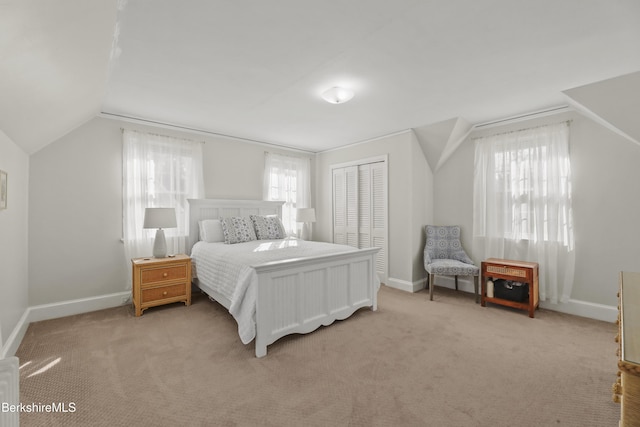 carpeted bedroom with a closet, baseboards, and vaulted ceiling