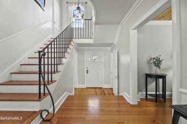 foyer entrance featuring stairs, hardwood / wood-style flooring, a chandelier, and ornamental molding