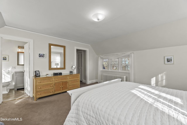 bedroom with ensuite bath, vaulted ceiling, radiator heating unit, and dark carpet