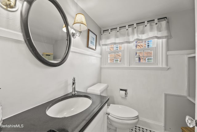 bathroom featuring toilet, vanity, and baseboards