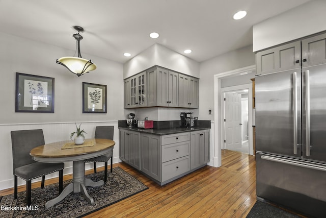 kitchen with hardwood / wood-style floors, dark countertops, high end fridge, and gray cabinetry