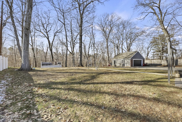 view of yard featuring a detached garage, an outdoor structure, and fence