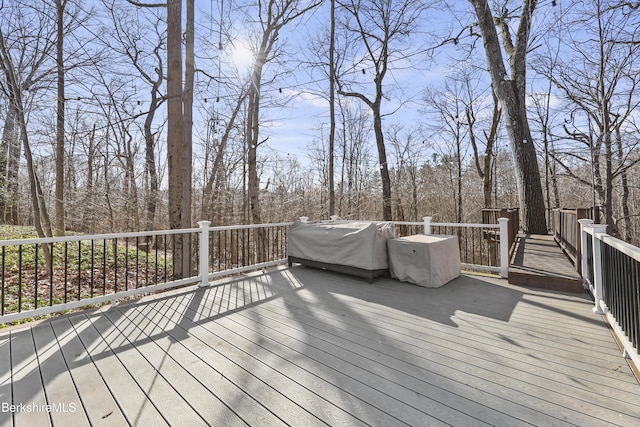 wooden deck with a forest view and a grill