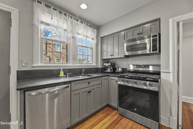 kitchen featuring dark countertops, gray cabinets, appliances with stainless steel finishes, and a sink