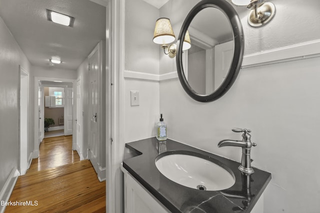 bathroom featuring baseboards, wood-type flooring, and vanity