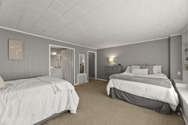 bedroom featuring ensuite bath, ornamental molding, and carpet flooring