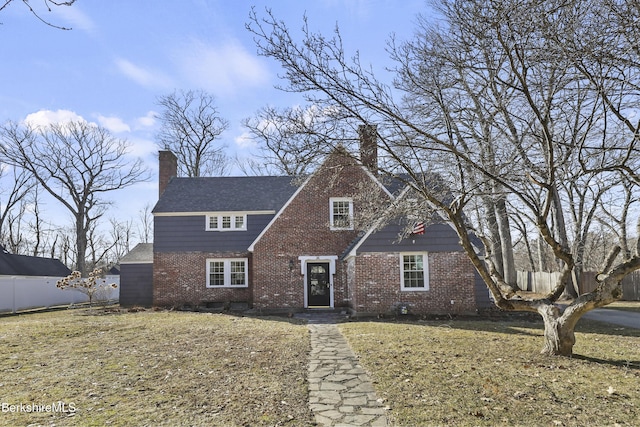 view of front of home with brick siding, a chimney, and fence