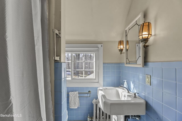 bathroom with a shower with shower curtain, radiator, a sink, wainscoting, and tile walls