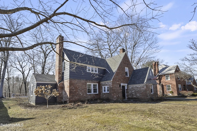 exterior space with a lawn, brick siding, and a chimney