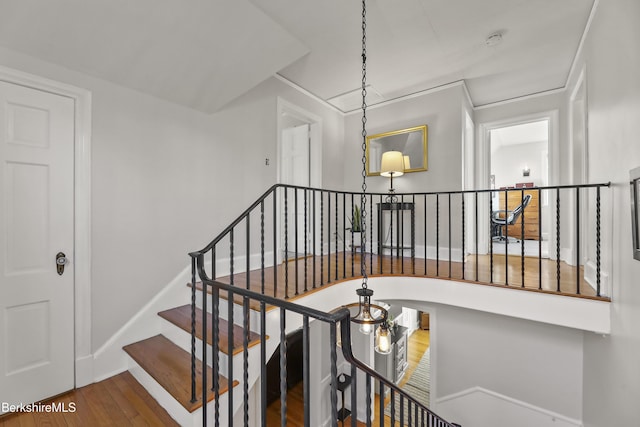 stairs with wood finished floors, baseboards, and arched walkways