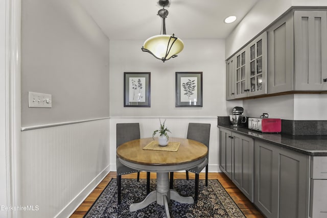 dining space featuring a wainscoted wall and dark wood-style flooring