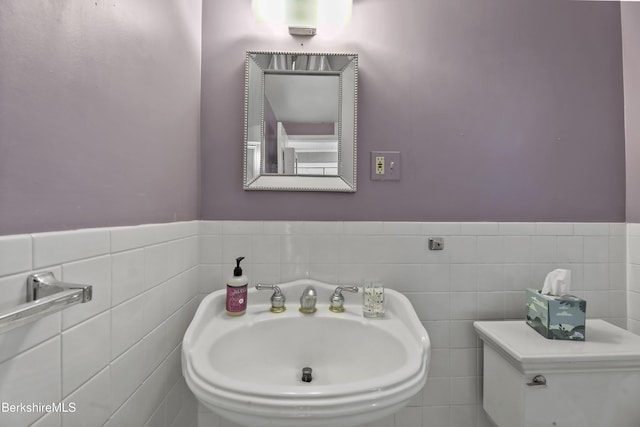 bathroom with a wainscoted wall, tile walls, and a sink