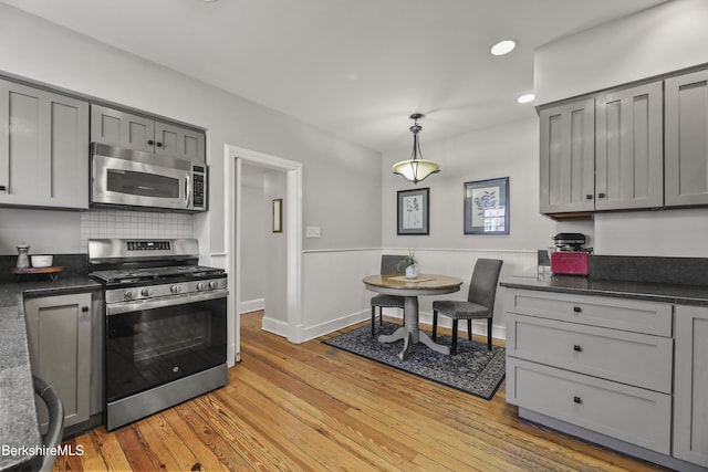 kitchen featuring stainless steel appliances, dark countertops, gray cabinets, and light wood finished floors