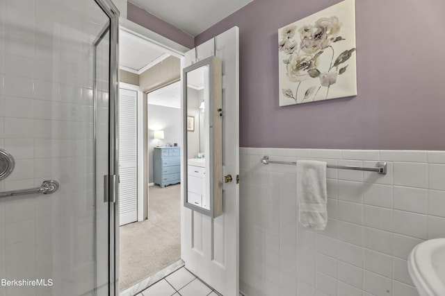 bathroom featuring tile patterned flooring, a shower stall, tile walls, and wainscoting