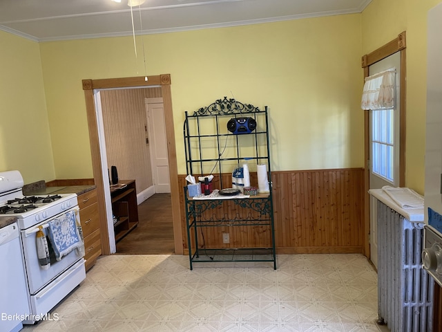 kitchen featuring crown molding, white appliances, and wooden walls