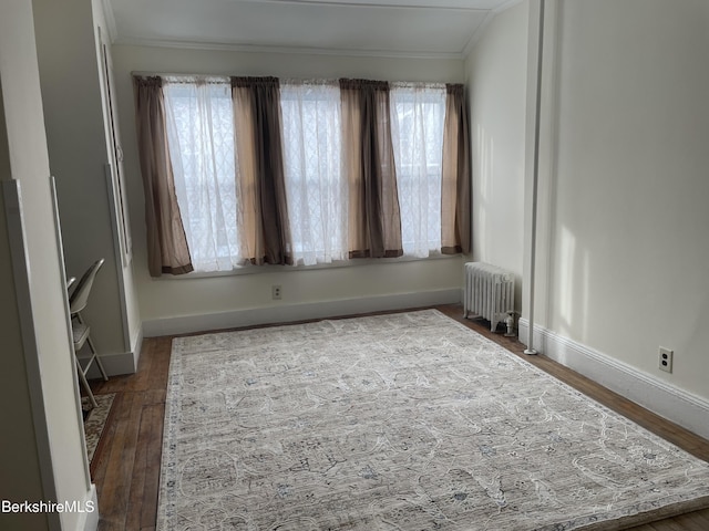 unfurnished room featuring hardwood / wood-style floors, crown molding, and radiator heating unit