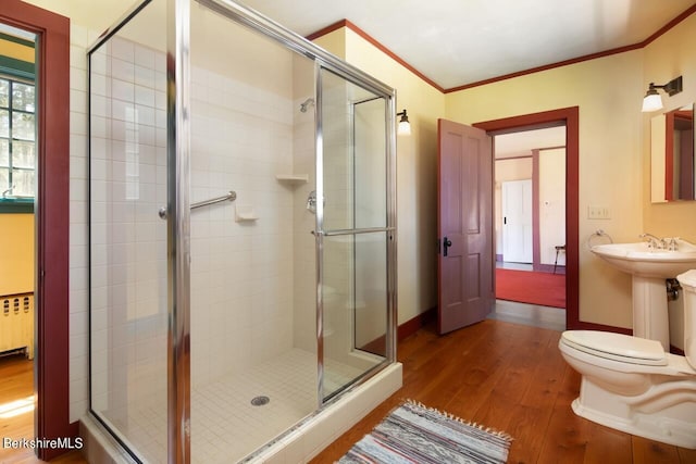 bathroom featuring hardwood / wood-style flooring, toilet, and a shower with shower door