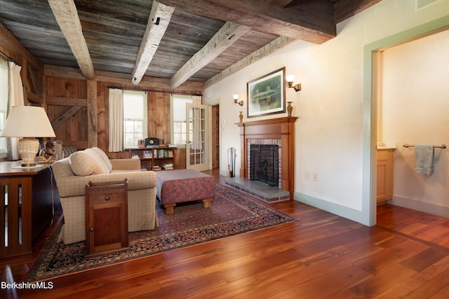 living room featuring beam ceiling, dark hardwood / wood-style flooring, wooden ceiling, and a brick fireplace