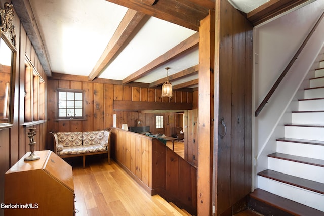 interior space featuring beam ceiling, wooden walls, and light hardwood / wood-style flooring