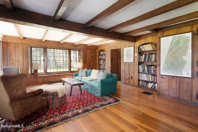 living room with hardwood / wood-style flooring, built in features, and beamed ceiling