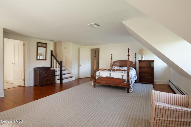 bedroom with dark hardwood / wood-style floors and a baseboard heating unit