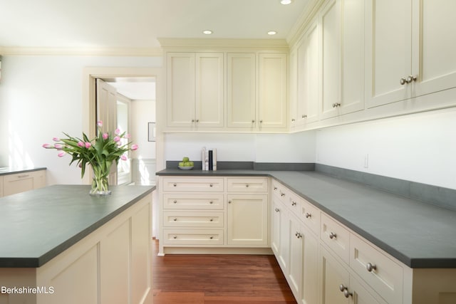 kitchen featuring cream cabinetry, dark wood-type flooring, and crown molding