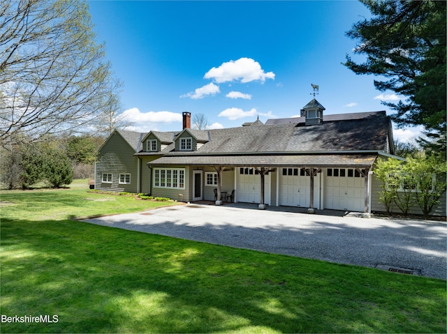 view of front of property featuring covered porch, a garage, and a front lawn