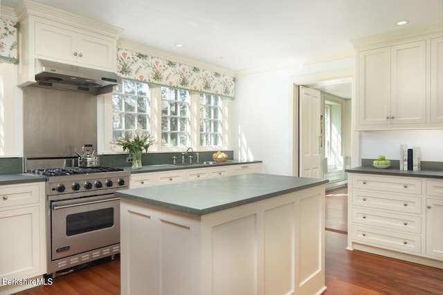 kitchen featuring luxury stove, crown molding, dark hardwood / wood-style flooring, white cabinetry, and extractor fan