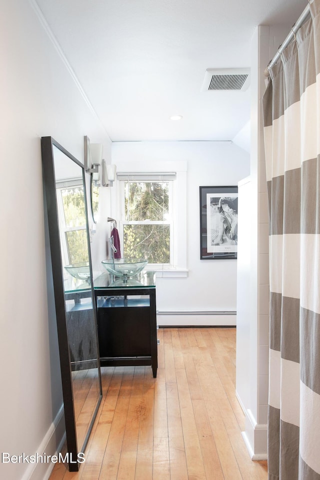 hallway featuring visible vents, a baseboard radiator, and light wood-type flooring