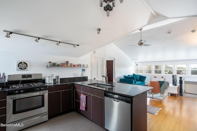 kitchen with a peninsula, open floor plan, vaulted ceiling with beams, a sink, and stainless steel appliances