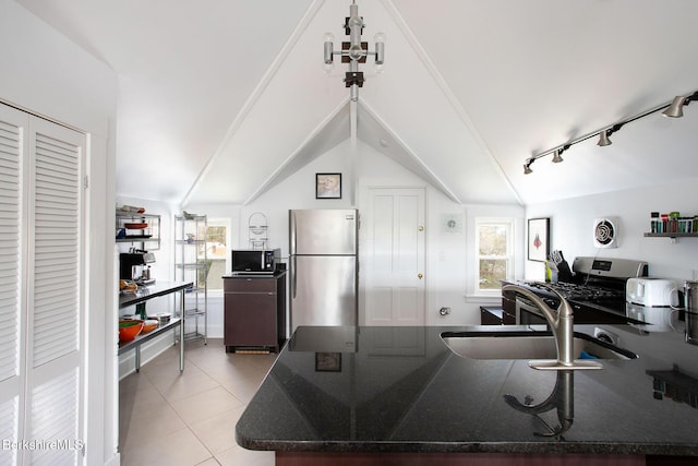 kitchen with plenty of natural light, light tile patterned floors, vaulted ceiling, and stainless steel appliances