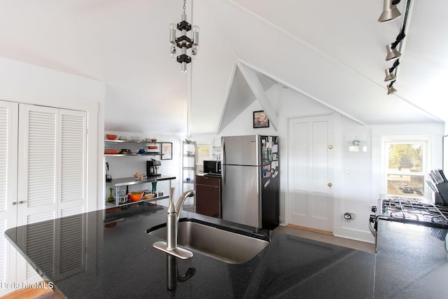 kitchen with dark countertops, a sink, freestanding refrigerator, baseboards, and lofted ceiling