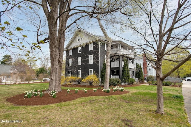 view of side of home featuring a lawn and a balcony