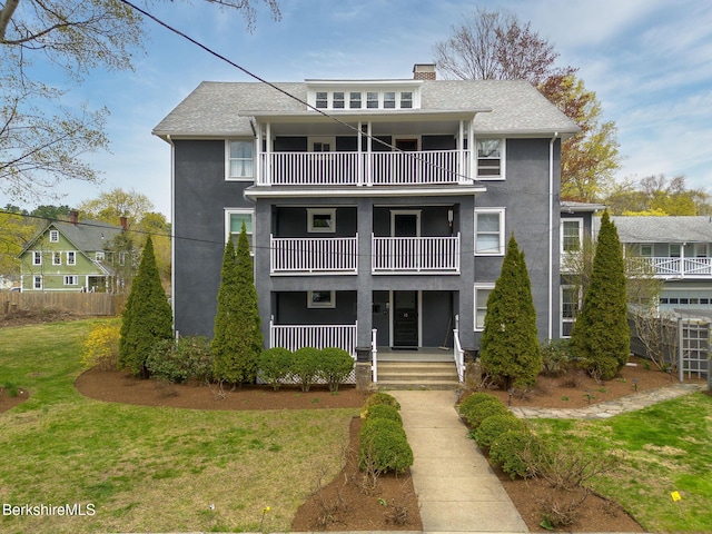 exterior space featuring fence, a balcony, a front yard, stucco siding, and a porch