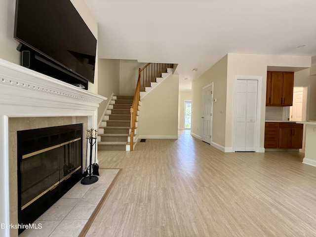 2 Copper Beech Ln, Great Barrington, MA 01230 - unfurnished living room featuring light wood finished floors, a tile fireplace, and stairway
