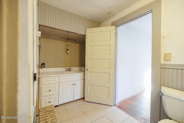 bathroom featuring toilet, a textured ceiling, vanity, and tile patterned floors