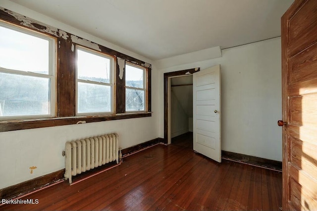 unfurnished bedroom featuring dark hardwood / wood-style floors and radiator heating unit