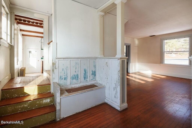 staircase featuring wood-type flooring and decorative columns