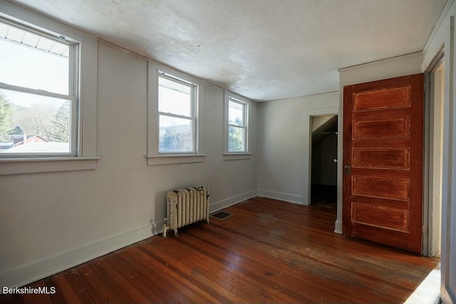 interior space featuring dark hardwood / wood-style floors, radiator heating unit, and a textured ceiling