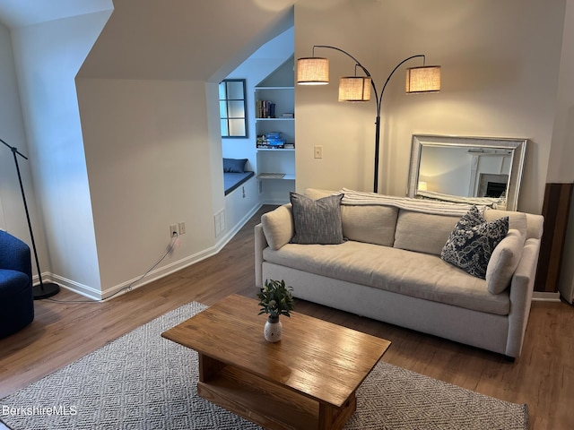 living room with built in shelves and hardwood / wood-style floors